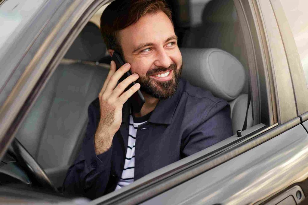Tracking Mileage for Taxes in 2022 3 young happy attractive successful bearded man sits car talking phone with his friend smiling broadly looking away min 11zon
